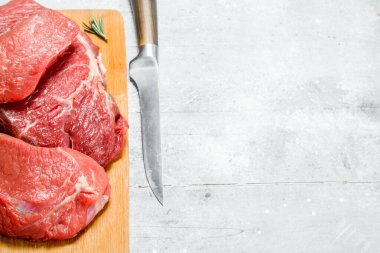 Çiğ et. Biberiye dalları ile taze et parçaları. Rustik bir arka plan üzerinde