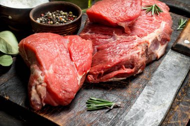 Çiğ et. Taze et baharat ve eski bir bıçak ile. Ahşap bir arka plan üzerinde.