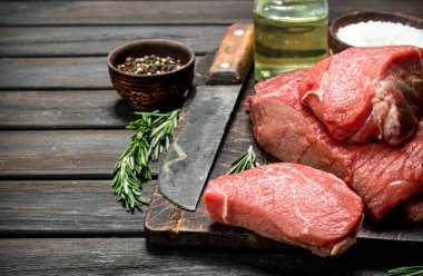 Çiğ et. Taze et baharat ve eski bir bıçak ile. Ahşap bir arka plan üzerinde.