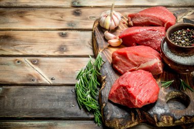 Çiğ et. Baharat ve otlar ile sığır eti adet dilimlenmiş. Ahşap bir arka plan üzerinde.