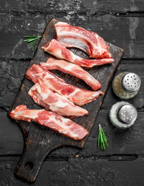 Baharat ile ham dilimlenmiş kaburga. Siyah bir rustik arka planda.