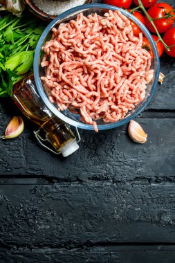 Çiğ kıyma yeşil maydanoz ve domates ile bir kase. Rustik siyah arka plan üzerine.