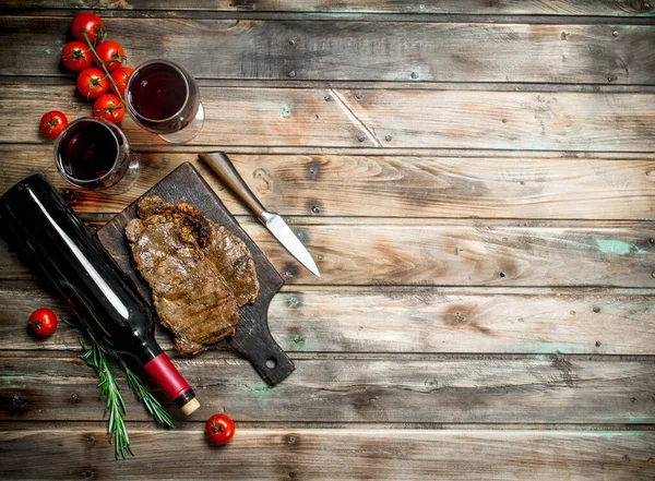 Roast beef steak with red wine. On a wooden background.