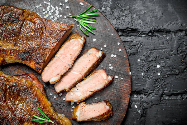 Grilled beef steaks on a cutting Board. On a black rustic background.