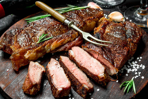 Grilled beef steak with rosemary and spices. On a black rustic background.