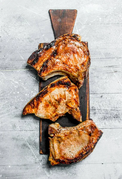 stock image Grilled pork steaks on cutting board. On a rustic background .