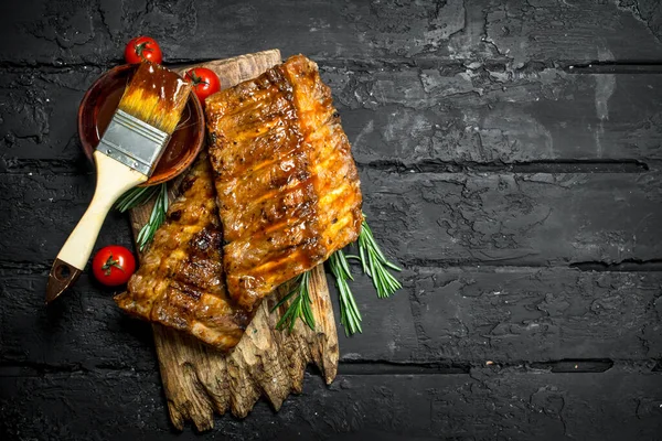 stock image Grilled ribs with sauce. On a black rustic background.