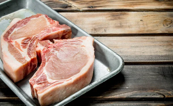 stock image Raw pork steaks on the bone. On a wooden background.