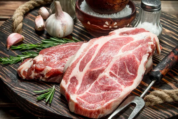 stock image Raw steaks from juicy pork. On a wooden background.