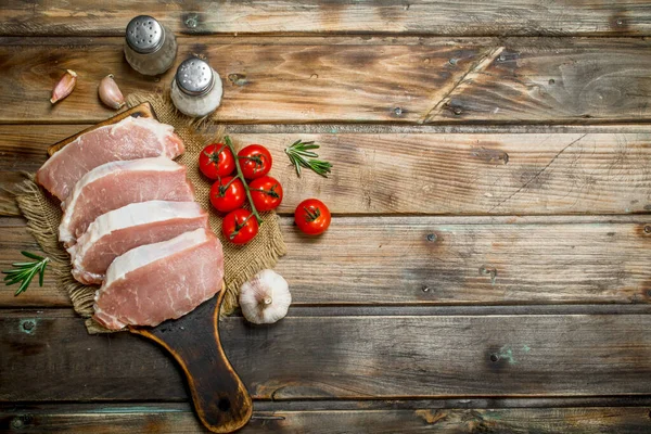 stock image Raw pork steaks with tomatoes and rosemary. On a wooden background.