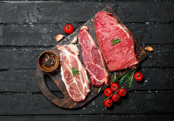 Surowe Mięso Wołowina Wieprzowina Steki Przyprawami Cięcia Pokładzie Czarnym Tle — Zdjęcie stockowe