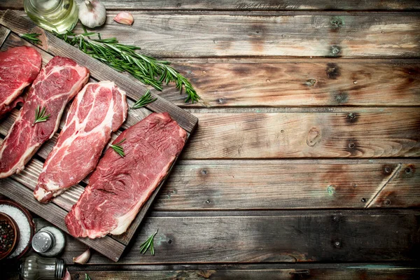 stock image Raw meat. Beef steaks and pork with spices. On a wooden background.