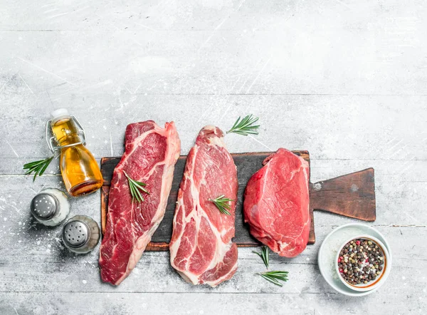 stock image Raw meat. Pieces of beef and pork with spices and herbs. On a rustic background.