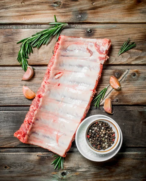 stock image Raw ribs with spices and herbs . On a wooden background.