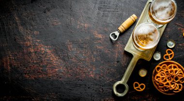 Bardaklarda bira, kasede atıştırmalık. Koyu rustik arka plan üzerinde