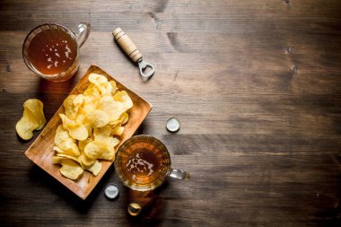 Bardak bardakta bira ve tabakta cips. Ahşap arka planda