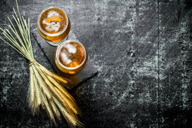 Bir standdaki bardaklı bira ve bir sürü çivi. Siyah rustik arka plan üzerinde