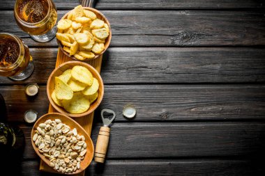 Kesme Tahtası üzerinde kaselerde bira ve aperatifler çeşitli. Siyah ahşap arka plan üzerinde