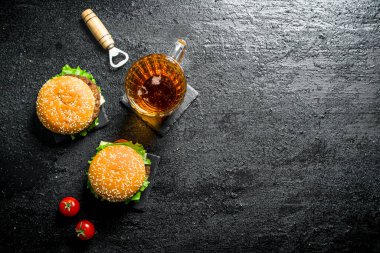 Bir bardak ve domates bira ile Burgers. Siyah rustik arka plan üzerinde