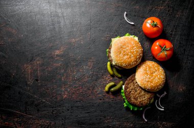 Gherkins ve domatesli hamburgerler. Koyu rustik arka plan üzerinde