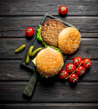 Bir dal ve gherkins üzerinde domates burger. Siyah ahşap arka plan üzerinde