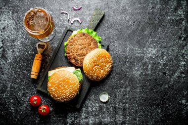 Hamburger ve bira. Siyah rustik arka plan üzerinde