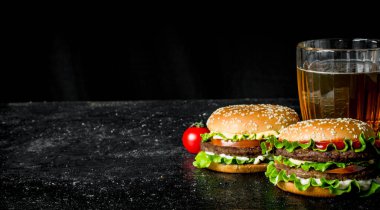 Bira ve domatesli hamburgerler. Siyah rustik arka plan üzerinde