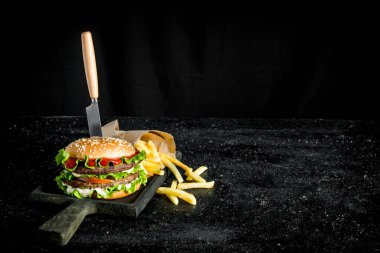 Bıçaklı burger ve patates kızartması. Rustik arka planda
