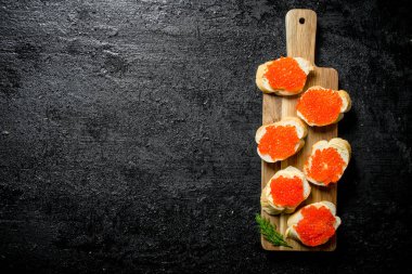 Dereotu ile kesme tahtası üzerinde kırmızı havyar ile Sandviçler. Siyah rustik arka plan üzerinde