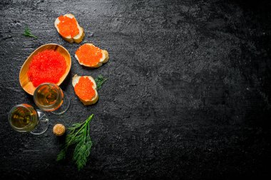 Bir kase ve şarap ve dereotu ile kırmızı havyar ile sandviç kırmızı havyar. Siyah rustik arka plan üzerinde