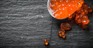 Kaşıkta kırmızı havyar taneleri. Siyah rustik arka plan üzerinde