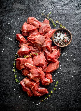 Kasede kekik ve baharatlar ile kesilmiş çiğ sığır eti. Siyah rustik arka plan üzerinde