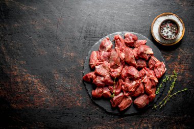 Kekik ve kaselerde baharatlar ile bir taş Tahta üzerinde kesilmiş çiğ sığır eti. Rustik arka planda