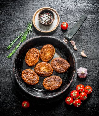 Biberiye, sarımsak ve domates ile tavada Pirzola. Siyah rustik arka plan üzerinde