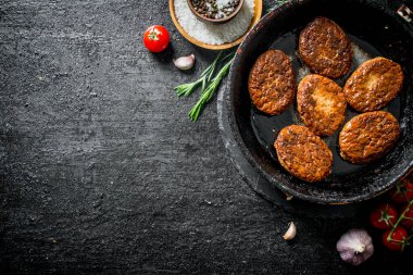 Biberiye, sarımsak ve domates ile tavada Pirzola. Siyah rustik arka plan üzerinde