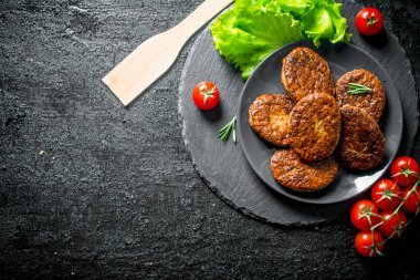 Salata yaprakları ve domates ile bir tabak tabaktabak tabaktabak tabaktabak ta. Siyah rustik arka plan üzerinde