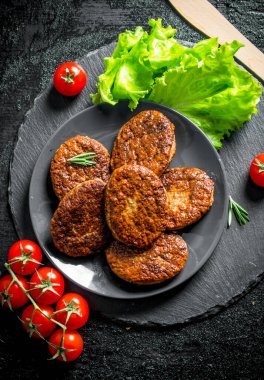 Salata yaprakları ve domates ile bir tabak tabaktabak tabaktabak tabaktabak ta. Siyah rustik arka plan üzerinde