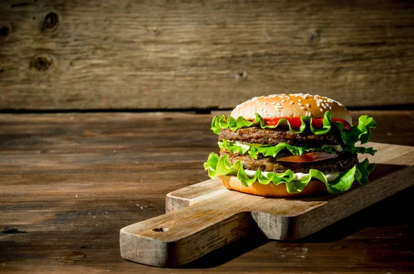 stock image One Burger with beef,salad and vegetables. On wooden background