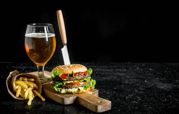 Burger Nożem Frytki Piwo Szklance Czarnym Tle Rustykalnym — Zdjęcie stockowe