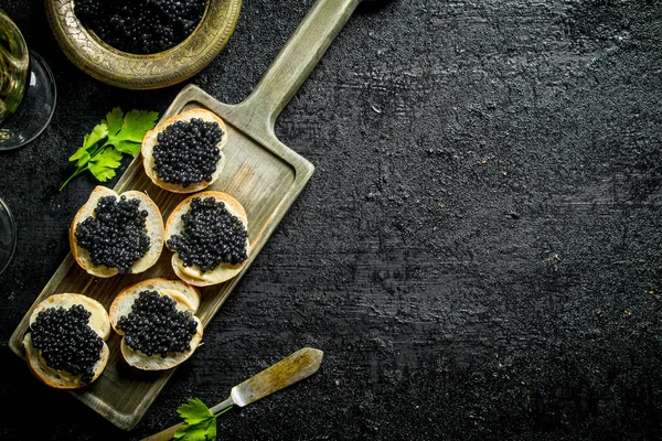 Sanduíches Com Caviar Preto Tábua Corte Fundo Rústico Preto — Fotografia de Stock
