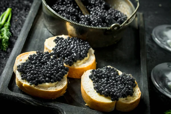 stock image Sandwiches with black caviar on the cutting Board. On black rustic background