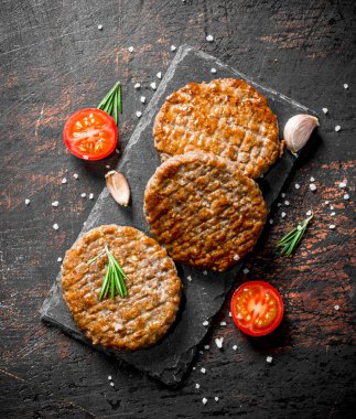 Sarımsak ve dilimlenmiş domates ile pirzola. Koyu rustik arka plan üzerinde