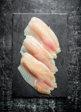 Siyah taş tahtaüzerinde balık filetosu. Siyah rustik arka plan üzerinde