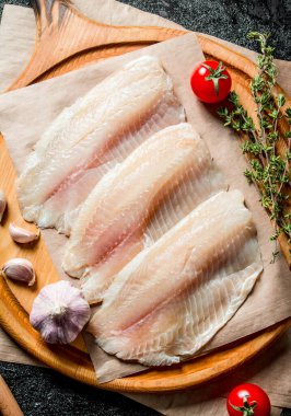 Sarımsak karanfil, domates ve kekik ile kesme Kurulu tilapia balık fileto. Rustik arka planda