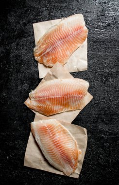 Kağıt peçetelerde balık filetosu parçaları. Siyah rustik arka plan üzerinde