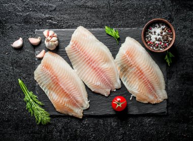 Kasede dereotu, domates ve baharatile siyah taş tahta üzerinde balık filetosu. Siyah rustik arka plan üzerinde