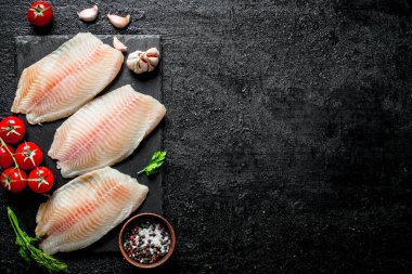 Kasede dereotu, domates ve baharatile siyah taş tahta üzerinde balık filetosu. Siyah rustik arka plan üzerinde