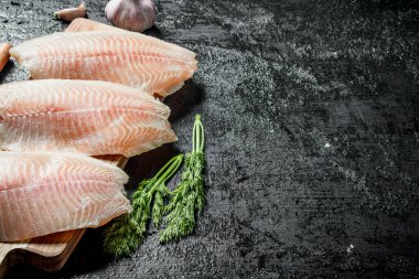 Dereotu ile Tilapia balık filetosu. Siyah rustik arka plan üzerinde