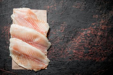 Kağıt üzerinde balık filetosu. Koyu rustik arka plan üzerinde