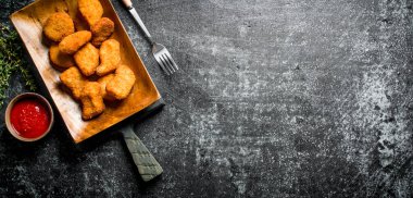 Çatallı bir tabakta tavuk külçeleri. Koyu rustik arka plan üzerinde